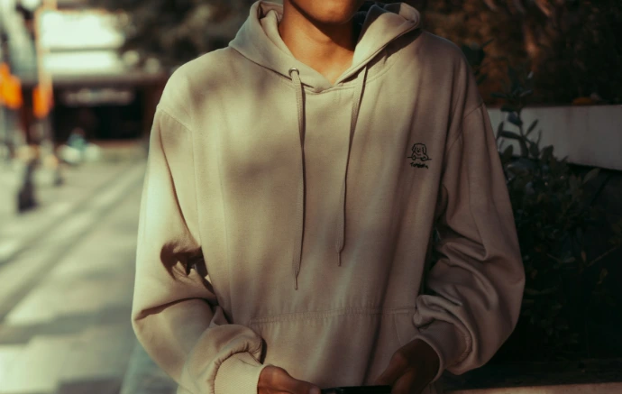 a man in a hoodie standing on a city street