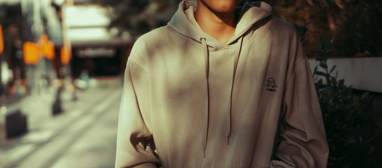 a man in a hoodie standing on a city street
