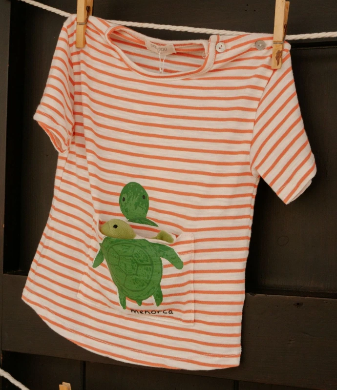 A child's shirt with turtles hangs on a clothesline.